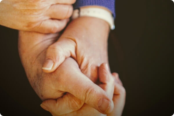 a closeup of a pair of seniors holding hands