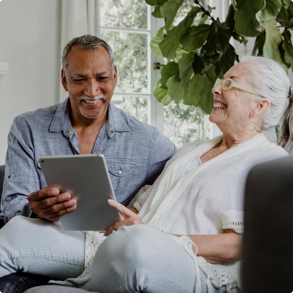 A senior couple laughing over an ipad