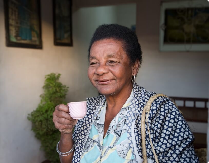 A smiling senior woman holding a pink teacup